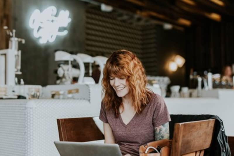 Mulher sentada em cadeira, montando negócio próprio na internet pelo computador. Como fazer negócios na internet através do marketing digital?