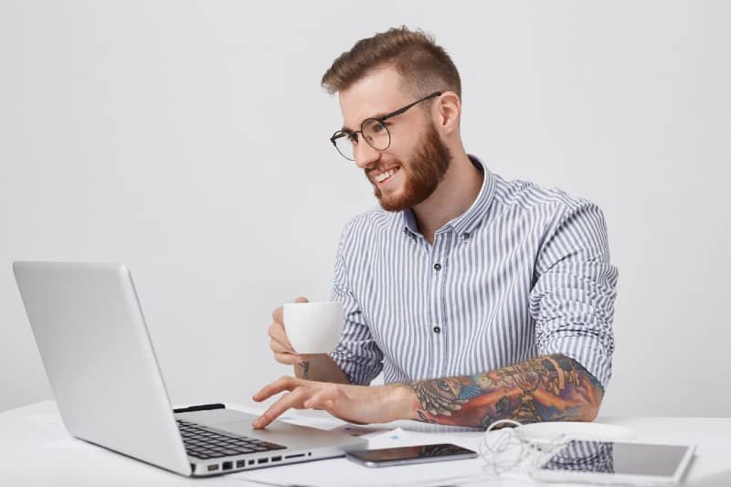 Homem sentado em frente a computador e celular do lado, marketing digital, estudo em casa, trabalho em casa, curso online