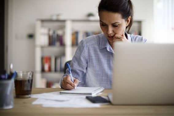 Menina sentada em frente a computador. Trabalhando ou estudando em casa. Home Office. Lugar calmo pra estudo ou trabalho.